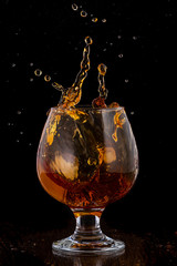 Splash in cognac glass from falling ice