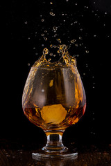 Splash in cognac glass from falling ice