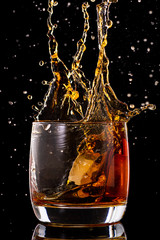 Splash in a glass from falling ice on a black background