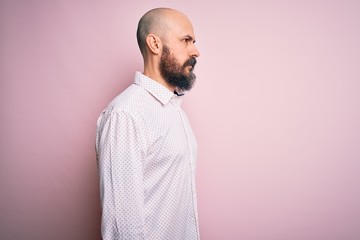 Obraz premium Handsome bald man with beard wearing elegant shirt over isolated pink background looking to side, relax profile pose with natural face with confident smile.