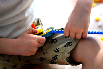 A young man in a white T-shirt, a little boy on the floor and collects the constructor on a sunny day ... entertainment