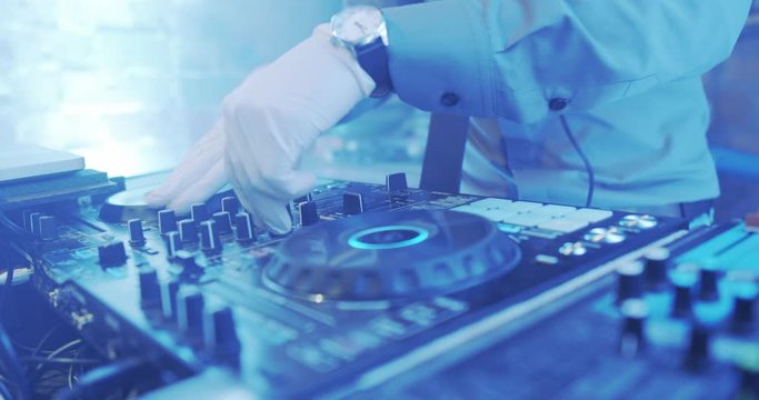 Charismatic disc jockey at the turntable. DJ plays on the best, famous CD players at nightclub during party. EDM, party concept