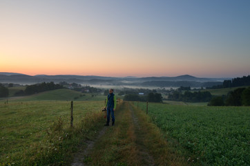Naklejka na ściany i meble photographer standing on a mountain road on an autumn morning