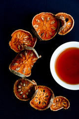 Top view of a cup of black tea surrounded with dried apple slices on dark blue background