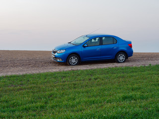 Obraz premium Belarus blue car in a field in spring at sunrise
