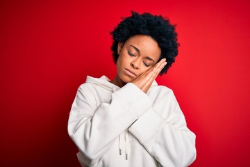 Fototapeta na wymiar Young beautiful African American afro sportswoman with curly hair wearing sportswear sleeping tired dreaming and posing with hands together while smiling with closed eyes.