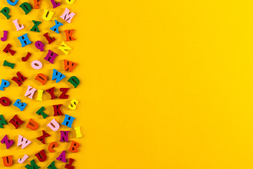 Multicolored alphabet background. Colorful letters of the English alphabet are scattered on yellow background. The concept of education in kindergarten and school. Learning the alphabet. Flat Lay
