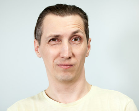Surprised facial expression with raised eyebrow in an adult man, grey background, emotions series