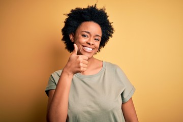 Fototapeta na wymiar Young beautiful African American afro woman with curly hair wearing casual t-shirt doing happy thumbs up gesture with hand. Approving expression looking at the camera showing success.