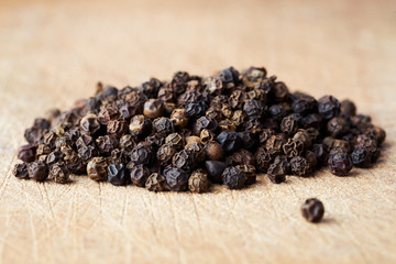 Closeup heap a whole pepper seeds on wooden background.