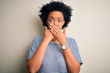 Young beautiful African American afro woman with curly hair wearing striped t-shirt shocked covering mouth with hands for mistake. Secret concept.