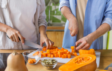 Unrecognizable couple cooking vegan food at home on the kitchen