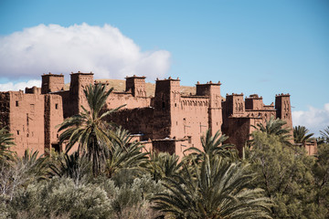 Fortaleza de Ait Ben Haddou en Marruecos con palmeras y un cielo azul