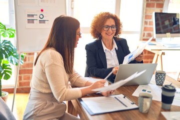 Two beautiful businesswomen smiling happy and confident. Sitting with smile on face working...