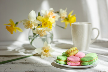 Fototapeta na wymiar a Cup of tea with macaroons morning Breakfast with a bouquet of flowers in a vase