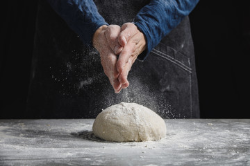 Thin male hands knead the dough for bread, pasta or pizza, close up. Closeup hand of chef baker kneading a dough. Male chef clapping hands with flour in kitchen 
