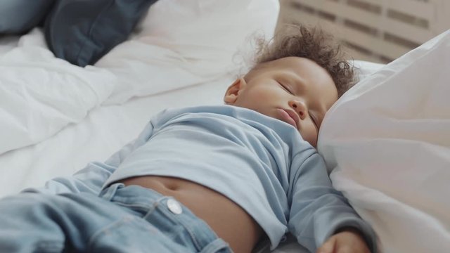 Close up of mixed-race sweet kid lying in bed and sleeping