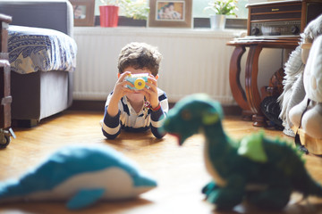 A boy takes pictures with his camera of his toys.