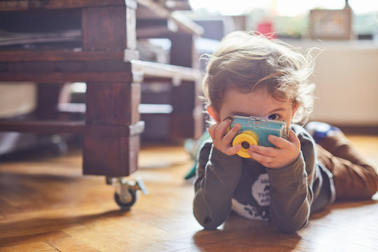a little boy takes pictures with his camera of his toys