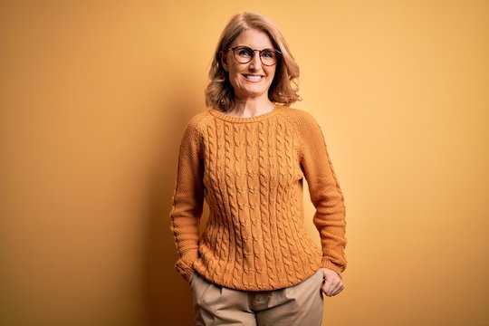 Middle Age Beautiful Blonde Woman Wearing Casual Sweater And Glasses Over Yellow Background With A Happy And Cool Smile On Face. Lucky Person.