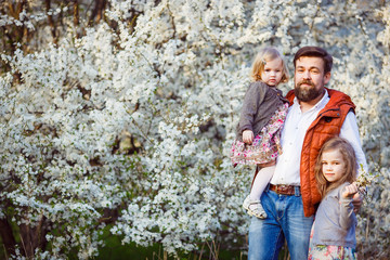 dad and daughters in flowering shrub white flowers