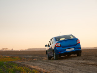 Fototapeta na wymiar Belarus blue car in a field in spring at sunrise