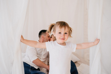 Cute kid daughter and dad tickling mom having fun good time playing together at home, happy parents...