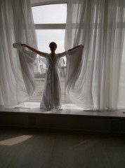 a girl in a dress plays with curtains