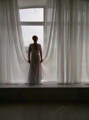 a girl in a dress plays with curtains