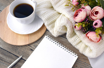 Coffee cup, notepad, roses and plaid on wooden background. Greeting card, feminine workplace or wedding checklist. Cozy still life composition with copyspace.