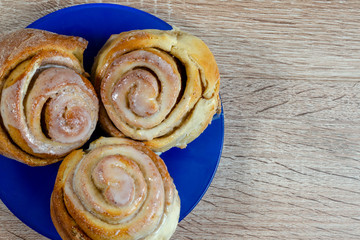 Homemade cinnamon rolls and cream on a baking sheet. blue plate selective focus