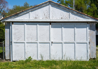 Old fashioned white garage with weathered peeling paint.