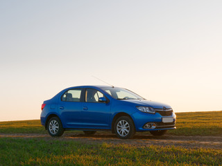 Obraz na płótnie Canvas Belarus blue car in a field in spring at sunrise