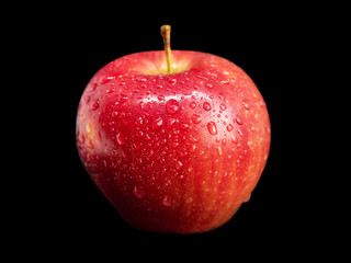 Beautiful red apple with drops of water on a black background