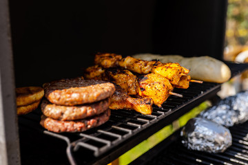 Burger patties, meat and baguettes on a Grill with aluminium foil
