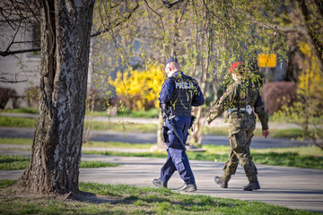 Policjant i żołnierz patrolują park w czasie epidemii. 