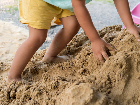 Little child boy playing and climbing sand pile outdoor with dirty foot, hand. Happy kid enjoy in relaxing day, preschool learning ef concept.