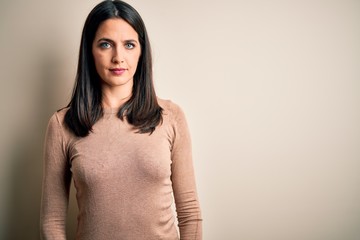 Obraz premium Young brunette woman with blue eyes wearing casual sweater over isolated white background Relaxed with serious expression on face. Simple and natural looking at the camera.