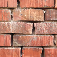Red brick wall with cracks and scratches. Old background texture. Vintage house facade.