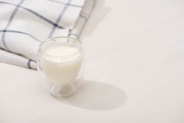 High angle view of glass of homemade yogurt near plaid fabric on white background