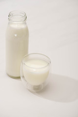 Obraz na płótnie Canvas High angle view of bottle and glass of homemade yogurt on white background