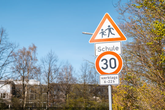 German attention school street sign with school and trees in background