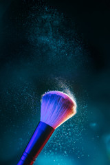 Makeup brush illuminated by blue, red and turquoise light.