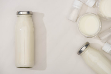 Top view of bottles and glasses of homemade yogurt and containers with starter cultures on white background