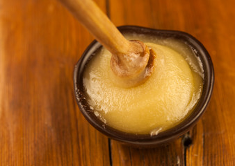 honey pour from a wooden spoon into a clay plate