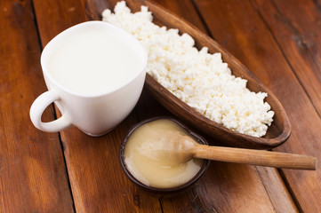 Cottage cheese in clay bowl and honey on wood table background. Dairy products and honey with copy space
