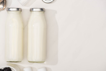 Top view of bottles of homemade yogurt on white background