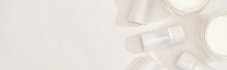 Top view of glasses of homemade yogurt near containers with starter cultures on white background, panoramic shot