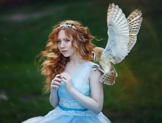 beautiful red-haired girl walks with an owl on her hand against the background of the castle