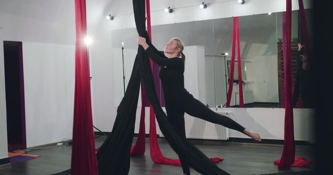 Female aerial yoga instructor performing an aerial dance on silks in gym
